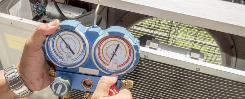 Technician checking refrigerant levels on an outdoor air conditioning unit at a Miami home with manifold gauges