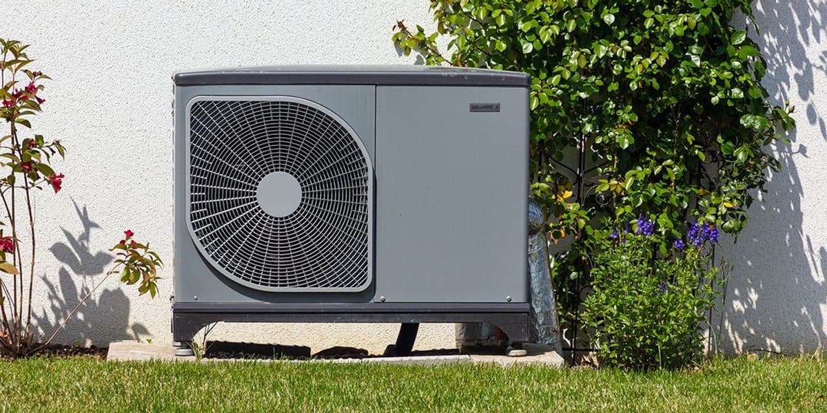 Heat pump outdoor unit with a round fan grille installed in the garden of a Miami home